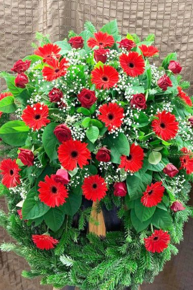 Trauerkranz mit roten Rosen und roten Gerberer